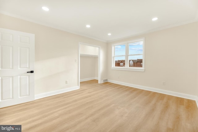 unfurnished bedroom with light hardwood / wood-style floors, a closet, and crown molding