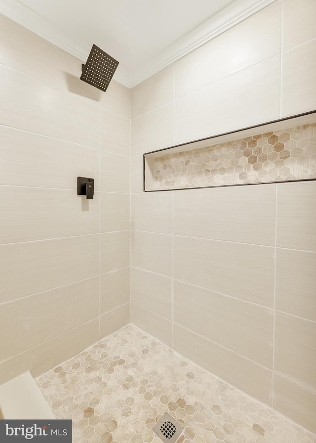 bathroom featuring tiled shower and crown molding