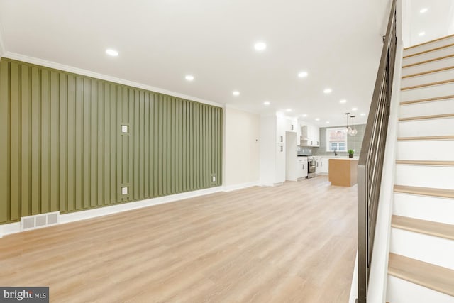 unfurnished living room featuring light hardwood / wood-style floors and crown molding