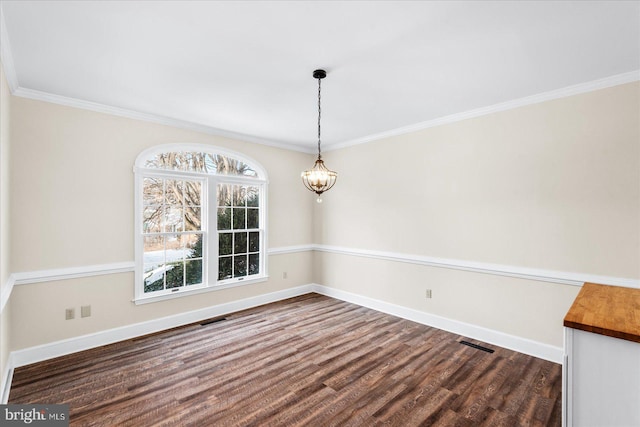 unfurnished dining area with crown molding, dark wood-type flooring, and a chandelier