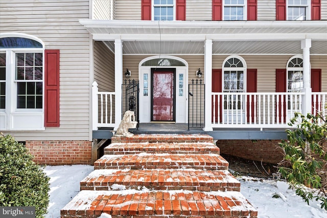 snow covered property entrance featuring a porch