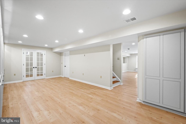 basement featuring french doors and light hardwood / wood-style floors