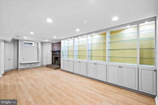 basement with light hardwood / wood-style flooring, a fireplace, and built in features