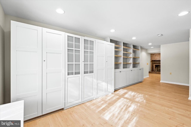 unfurnished living room with a brick fireplace and light hardwood / wood-style floors