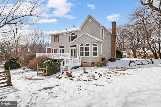 snow covered back of property featuring central AC and a deck