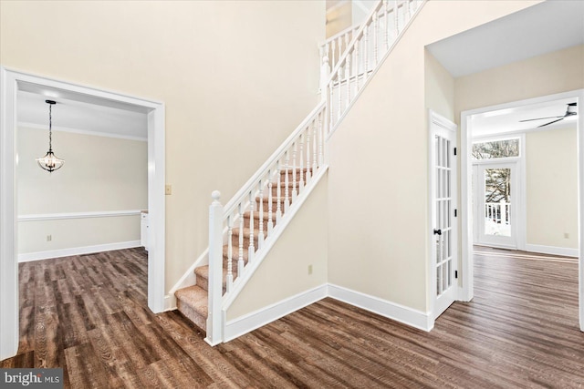 staircase with a towering ceiling, hardwood / wood-style floors, and ceiling fan