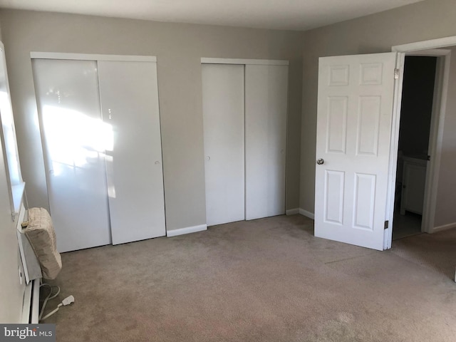 unfurnished bedroom featuring light carpet and multiple closets