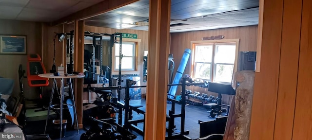 gym with a paneled ceiling and wooden walls