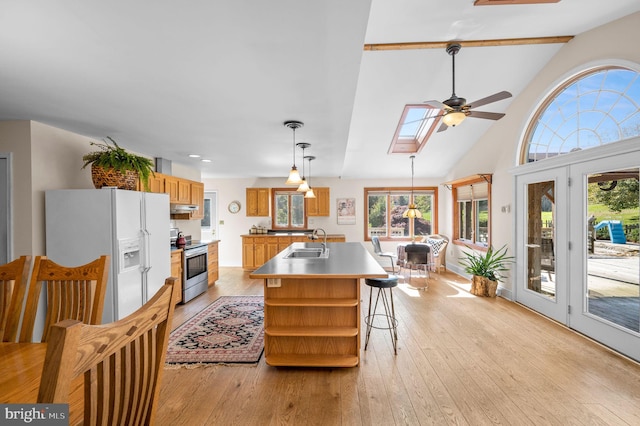 kitchen featuring a skylight, sink, hanging light fixtures, white refrigerator with ice dispenser, and stainless steel range with electric stovetop