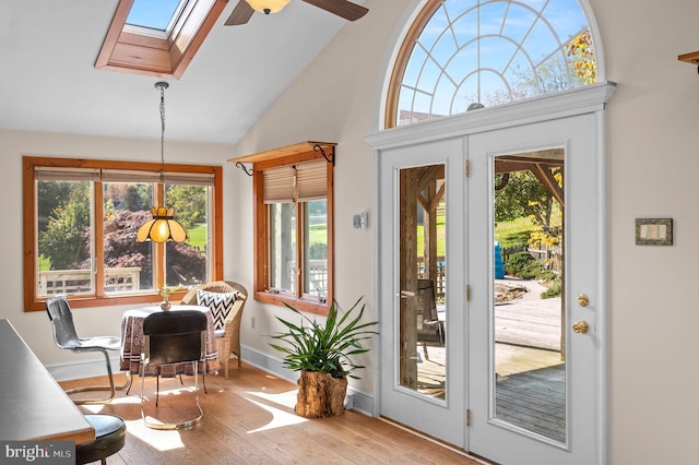 doorway to outside with ceiling fan, light hardwood / wood-style floors, plenty of natural light, and lofted ceiling with skylight