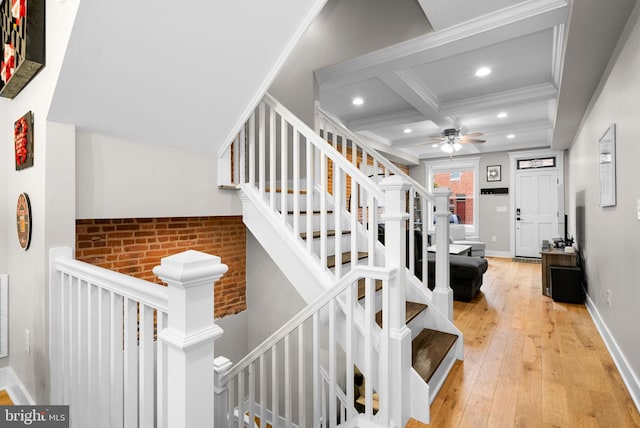 stairway with coffered ceiling, crown molding, hardwood / wood-style flooring, ceiling fan, and beamed ceiling