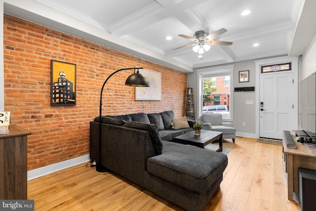 living room with beam ceiling, ceiling fan, coffered ceiling, light hardwood / wood-style flooring, and brick wall