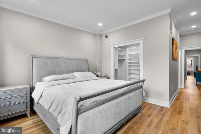 bedroom featuring crown molding, a spacious closet, a closet, and light hardwood / wood-style floors