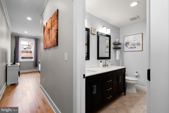 bathroom with wood-type flooring, vanity, toilet, and crown molding