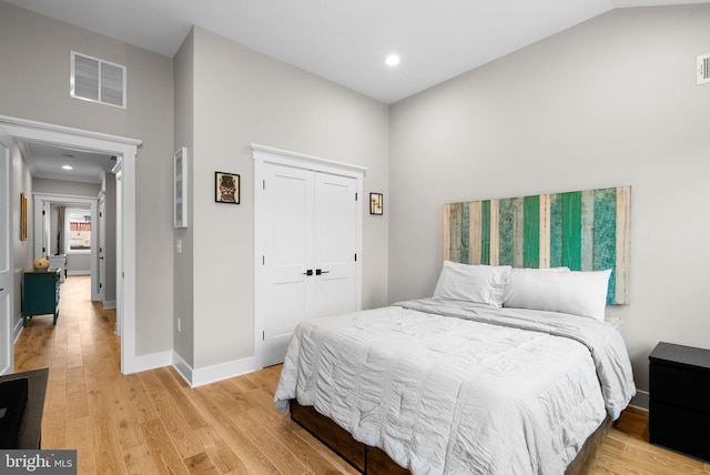 bedroom featuring a closet, lofted ceiling, and light hardwood / wood-style flooring