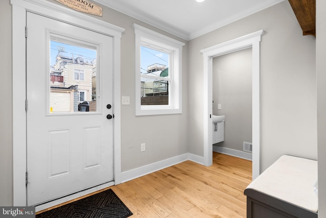 doorway with ornamental molding and light hardwood / wood-style flooring