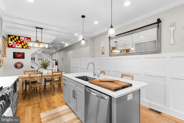 kitchen with appliances with stainless steel finishes, pendant lighting, ornamental molding, and sink