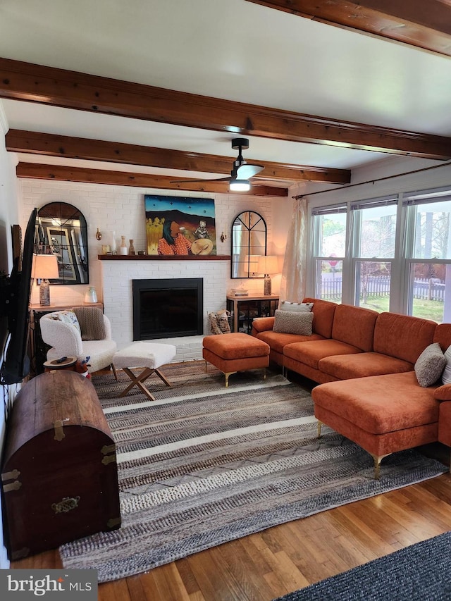 living room with hardwood / wood-style floors, beam ceiling, a fireplace, and ceiling fan