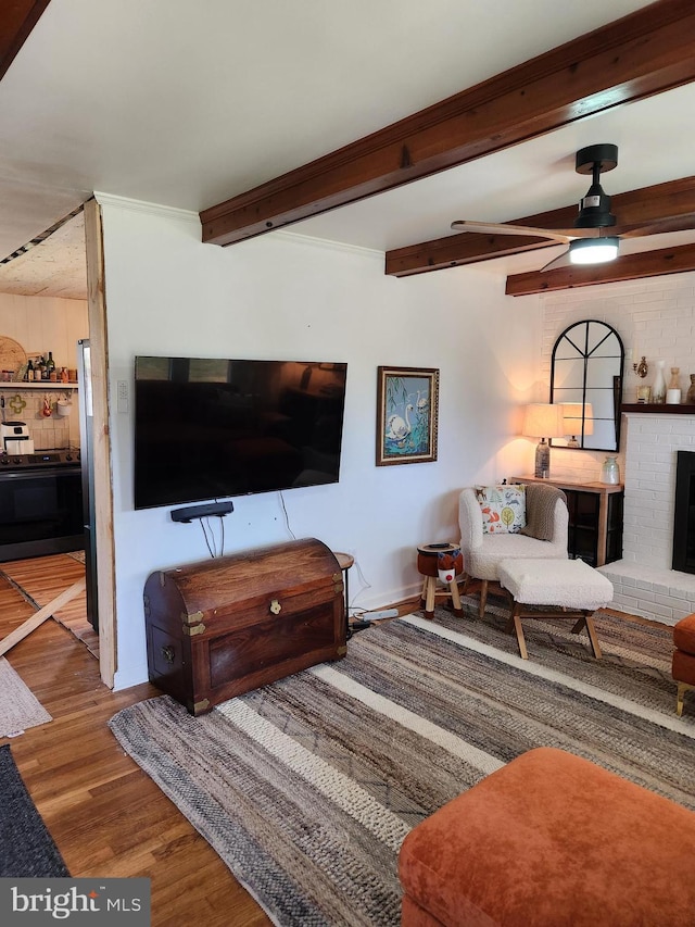 living room with ceiling fan, hardwood / wood-style flooring, a fireplace, and beamed ceiling