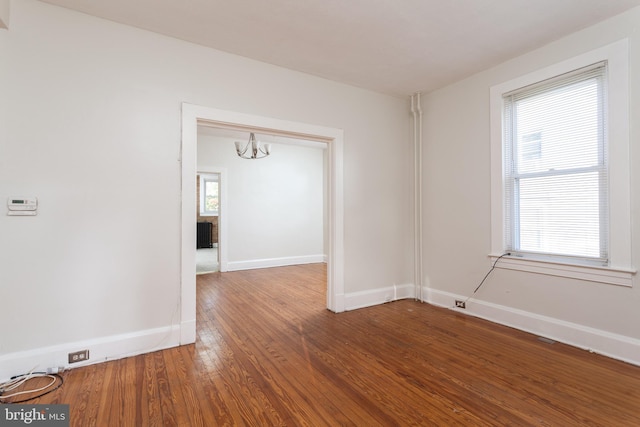 unfurnished room with hardwood / wood-style flooring and a chandelier