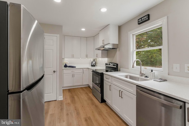 kitchen with stainless steel appliances, white cabinetry, light hardwood / wood-style floors, and sink