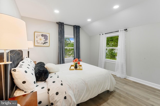 bedroom with light hardwood / wood-style flooring, vaulted ceiling, and multiple windows