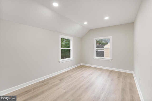 unfurnished room with light wood-type flooring and vaulted ceiling