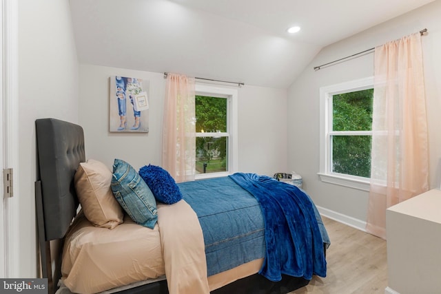 bedroom featuring light hardwood / wood-style floors, multiple windows, and vaulted ceiling