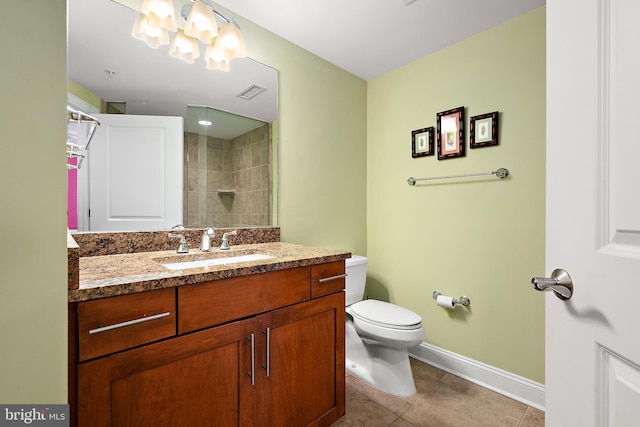 bathroom featuring tile patterned flooring, a tile shower, vanity, and toilet