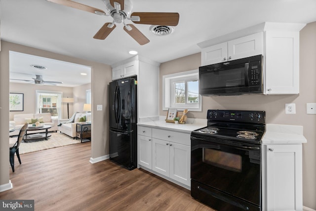 kitchen featuring a wealth of natural light, white cabinets, and black appliances