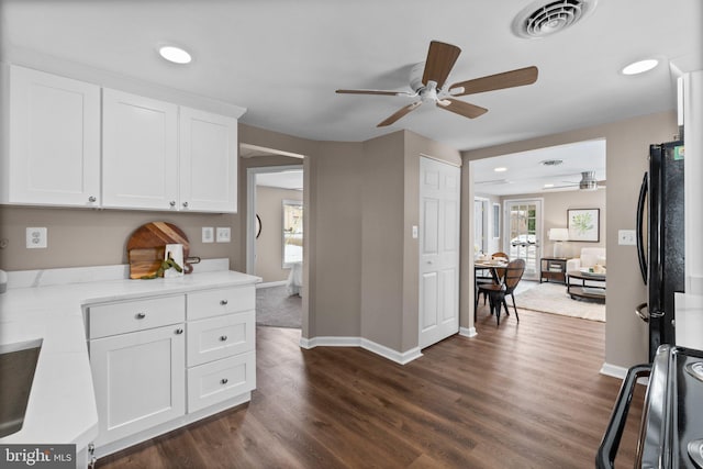 kitchen with range, white cabinetry, dark hardwood / wood-style floors, black fridge, and ceiling fan