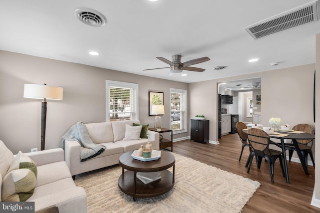 living room with ceiling fan and dark hardwood / wood-style floors