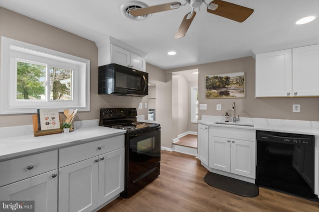 kitchen with light stone countertops, sink, white cabinetry, and black appliances