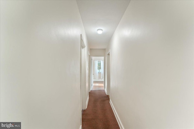 hallway featuring dark colored carpet