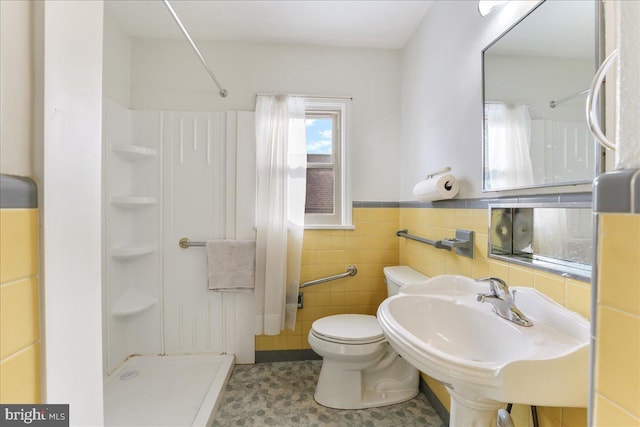 bathroom with sink, toilet, tile walls, and walk in shower