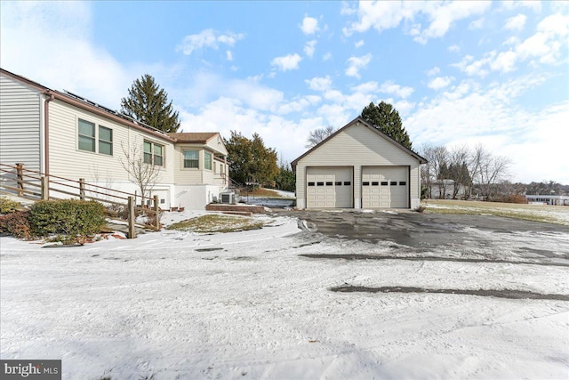 view of snowy exterior featuring a garage and an outdoor structure