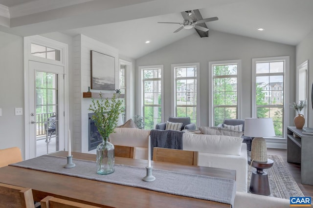 dining room with vaulted ceiling with beams, ceiling fan, a large fireplace, and wood-type flooring