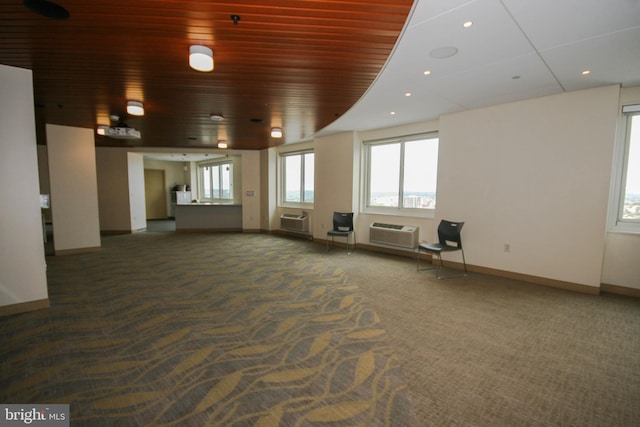 interior space featuring dark colored carpet, wood ceiling, and a wall unit AC