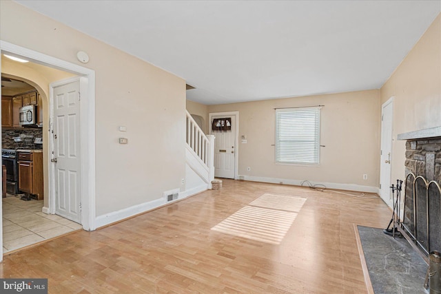 foyer featuring a stone fireplace and light wood-type flooring