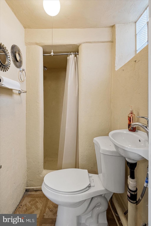 bathroom with sink, parquet flooring, toilet, and walk in shower