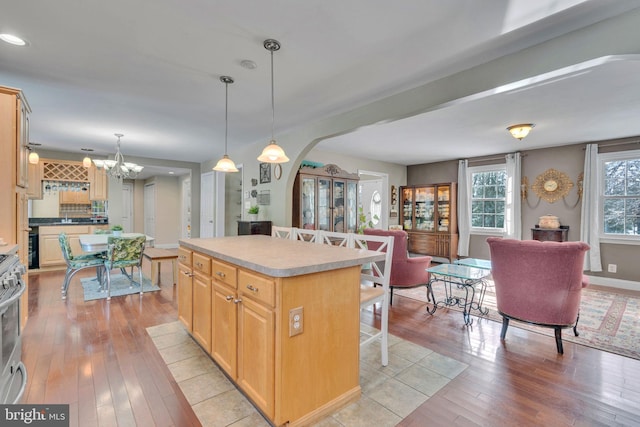 kitchen featuring light brown cabinetry, a breakfast bar area, decorative light fixtures, light hardwood / wood-style flooring, and a kitchen island