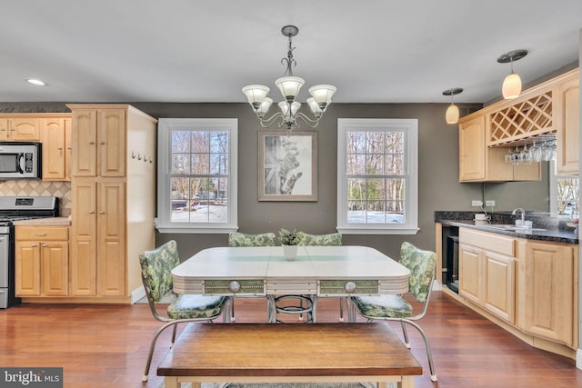 kitchen featuring stainless steel appliances, hanging light fixtures, sink, and light brown cabinets