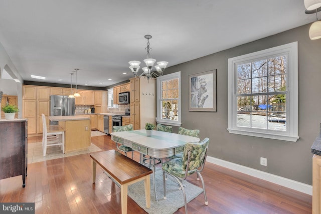 dining space with light hardwood / wood-style flooring and a notable chandelier