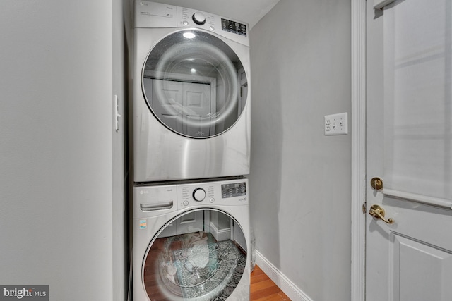 washroom featuring hardwood / wood-style flooring and stacked washer / dryer