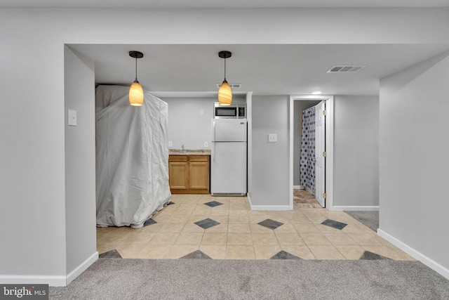 kitchen with hanging light fixtures, light tile patterned flooring, and white fridge