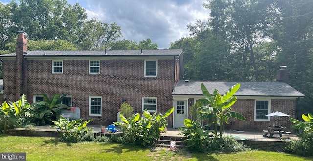 back of property with a yard and a patio area