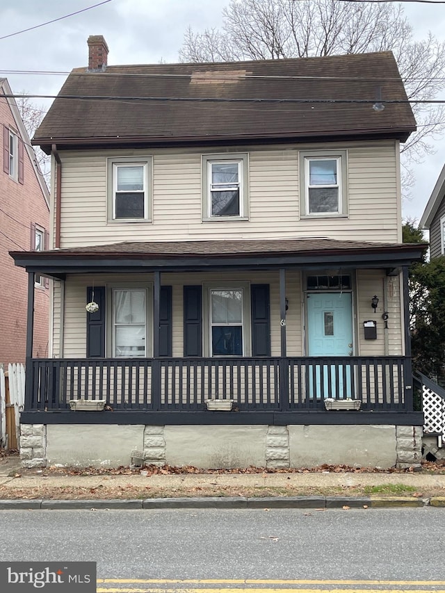 view of front of home with a chimney, a porch, and roof with shingles