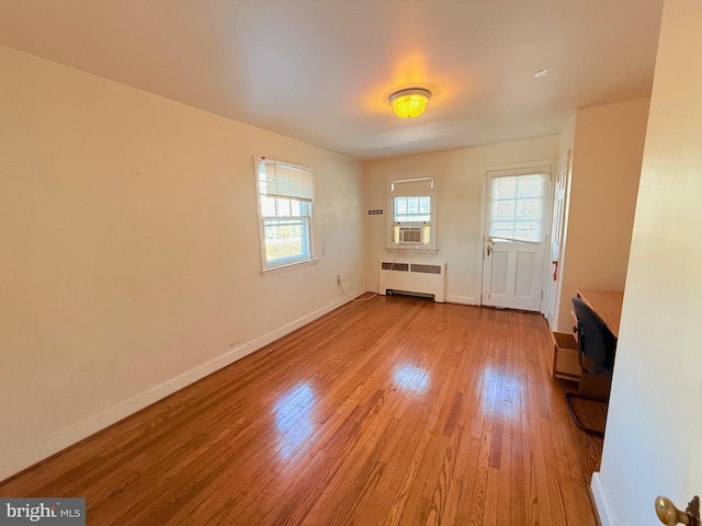 unfurnished living room featuring light hardwood / wood-style floors, radiator, and cooling unit