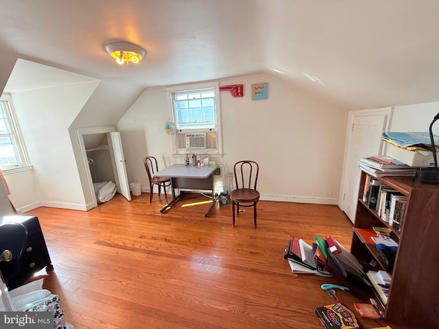 sitting room featuring light wood-type flooring, cooling unit, and lofted ceiling