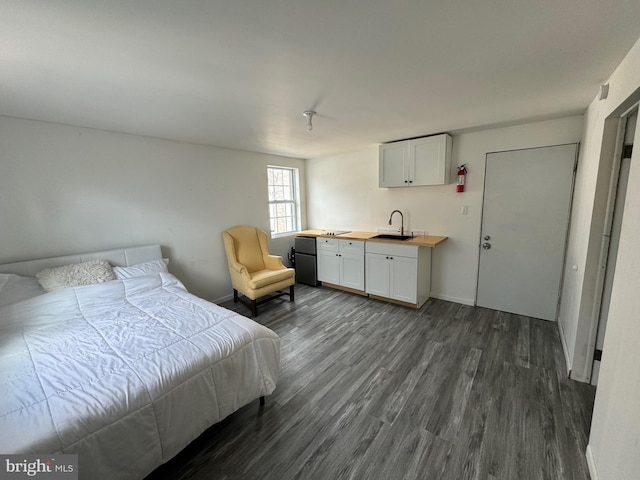 bedroom featuring sink, dark wood-type flooring, and fridge